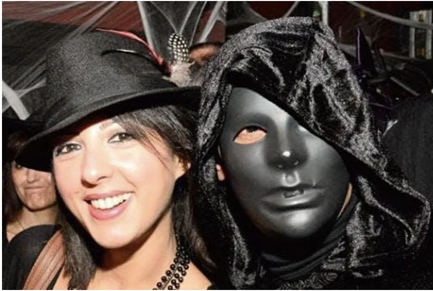 Two Halloween partygoers in a witch hat and black mask
